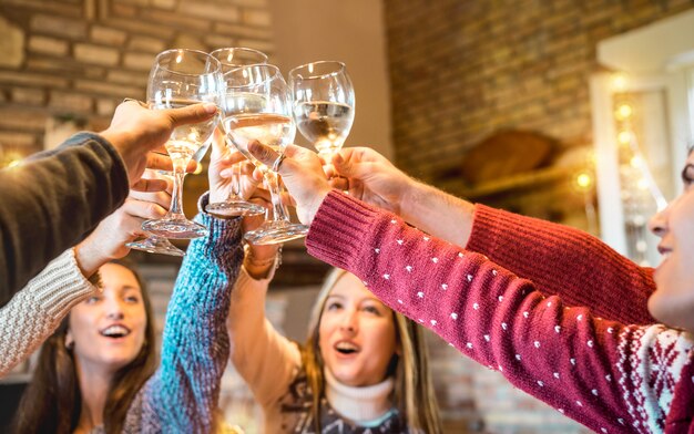 Amici felici che celebrano il natale tostando il vino champagne a casa cena