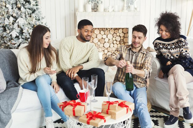 Happy friends celebrating New Year, opening champagne before midnight, copy space