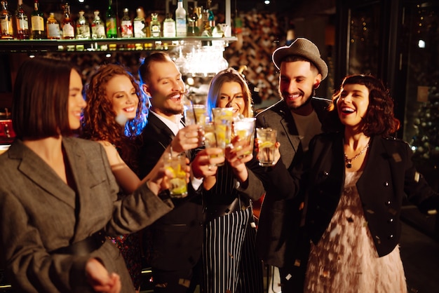 Amici felici che applaudono e bevono cocktail godendosi la festa nel club concetto di stile di vita giovanile