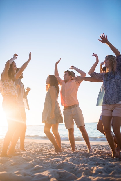 Happy friends dancing on the sand