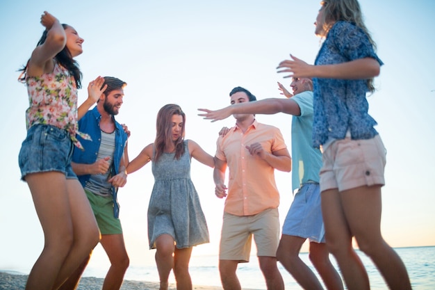 Happy friends dancing on the sand