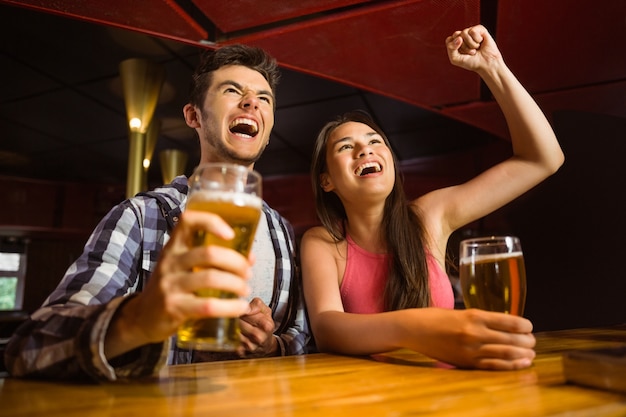 Happy friends drinking beer and cheering together