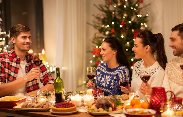happy friends drinking red wine at christmas party