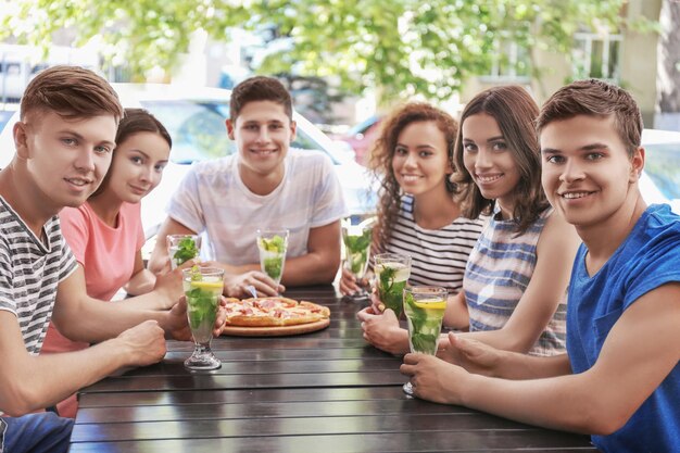 Happy friends eating pizza in cafe