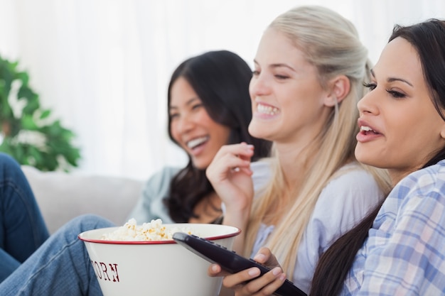 Happy friends eating popcorn and watching tv