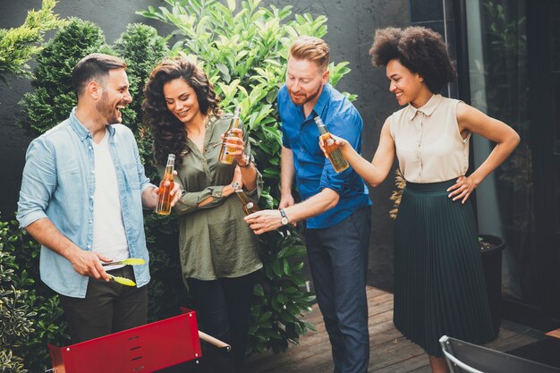 Happy friends grilling food and enjoying barbecue party outdoors