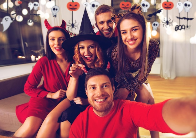 ハロウィーンの衣装を着た幸せな友達がセルフィーを撮っている