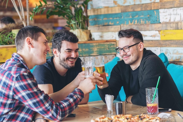 レストランのテーブルに座っている幸せな友達が飲み物を飲んでいる