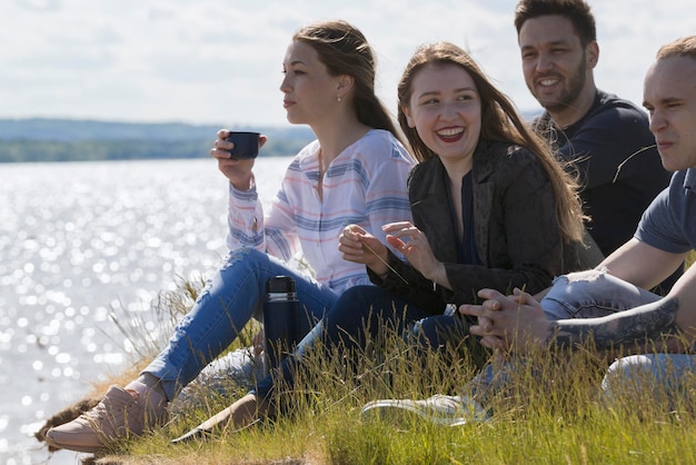 Happy friends having fun on the hill over the river enjoying recreation and talking