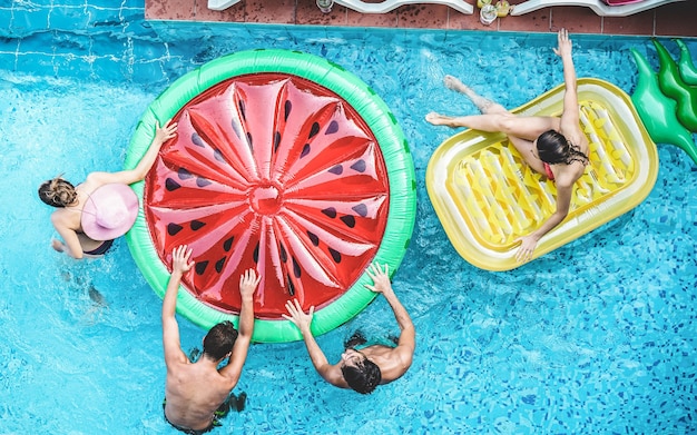 Photo happy friends having fun inside swimming pool during summer vacation - focus on heads