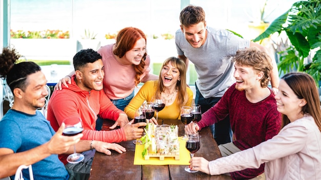 Amici felici che si divertono insieme a bere vino sul tetto durante una festa in casa privata