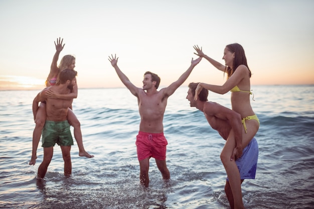 Happy friends having fun in the water at the beach