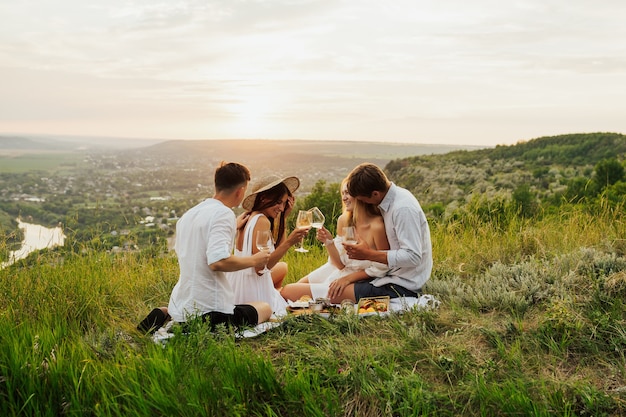 Счастливые друзья на холме, пикник в солнечный летний день.