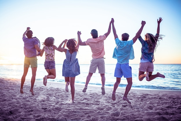 Happy friends holding hands and jumping