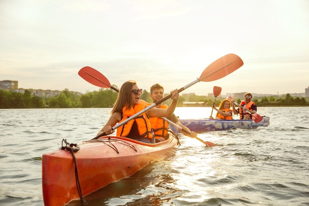 Amici felici in kayak sul fiume con il tramonto sullo sfondo