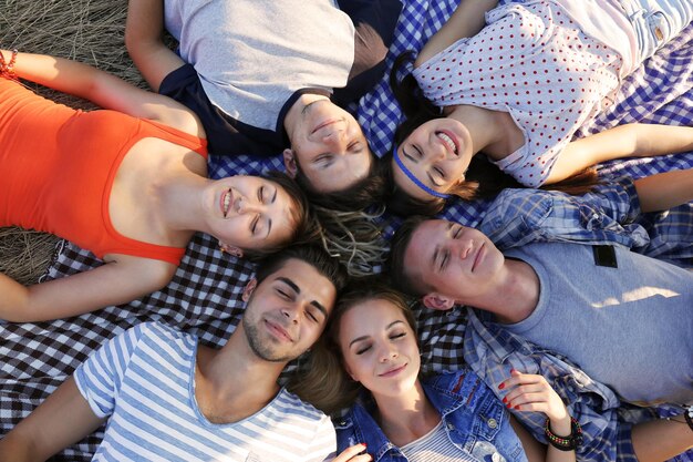 Happy friends lying headtohead on the blanket close up