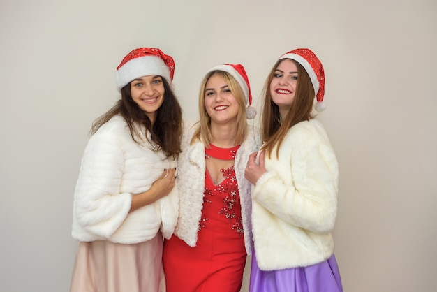 새해 파티를 축하하는 행복한 친구들. 우아한 이브닝 드레스와 모피 재킷을 입은 세 명의 여성