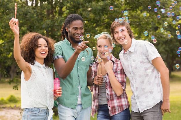 Happy friends in the park blowing bubbles