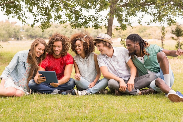 Happy friends in the park looking at tablet