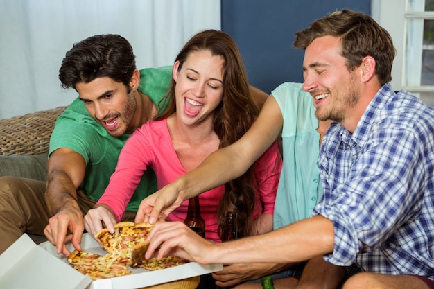 Photo happy friends picking up piece of pizza