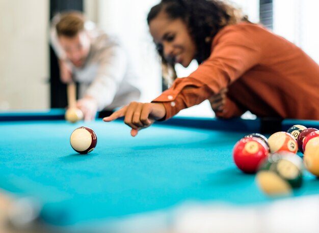 Happy friends playing pool together