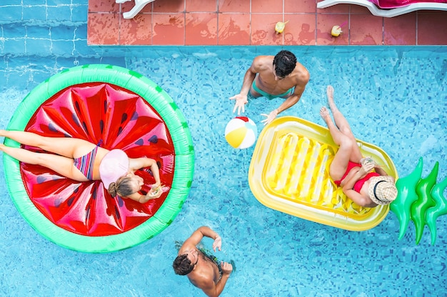 Happy friends playing with air lilo ball inside swimming pool