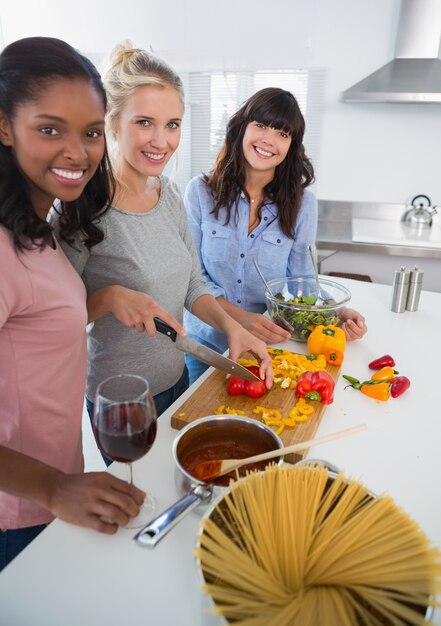 Happy friends preparing a meal together looking at camera