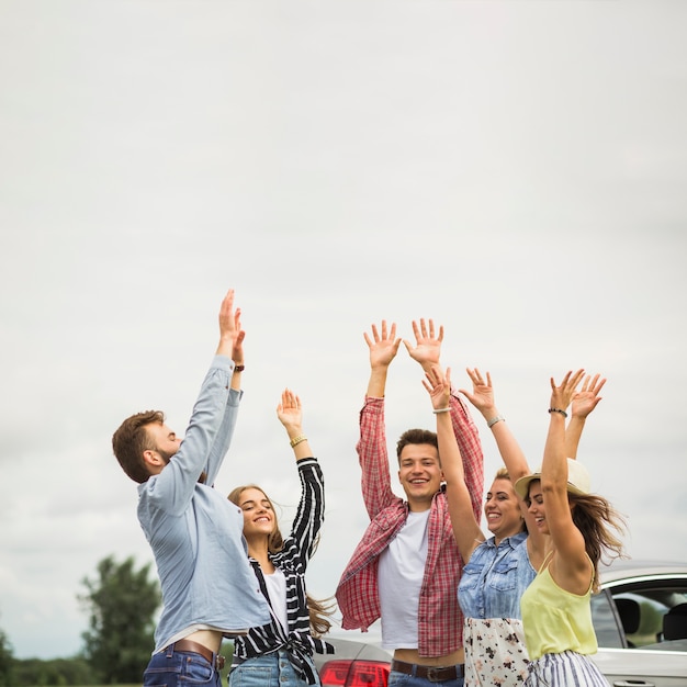 Happy friends raising their hands at outdoors