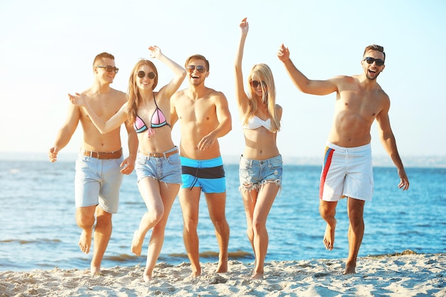 Amici felici che corrono in spiaggia all'aperto