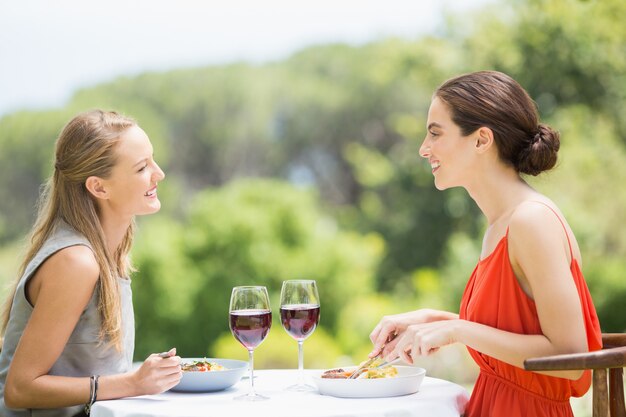 Amici felici che sorridono mentre mangiando cibo