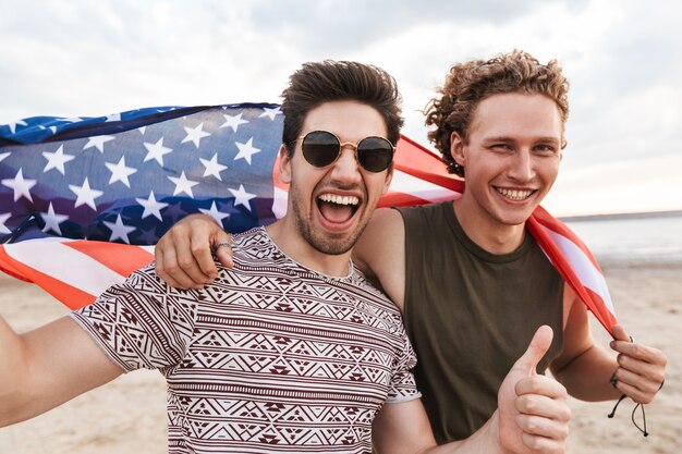 Photo happy friends spending time at the beach, holding american flag