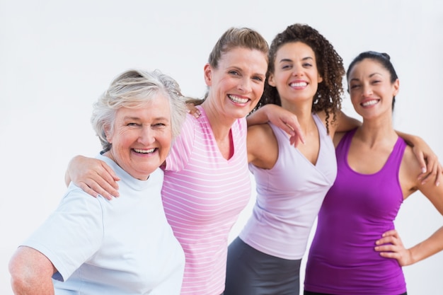 Happy friends standing arms around in fitness studio