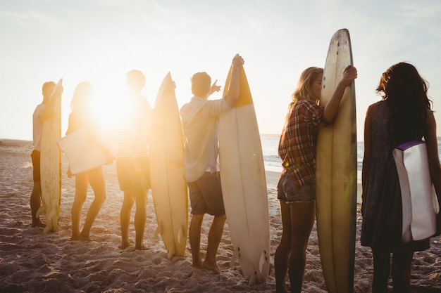 Счастливые друзья стоят в очереди с досками для серфинга