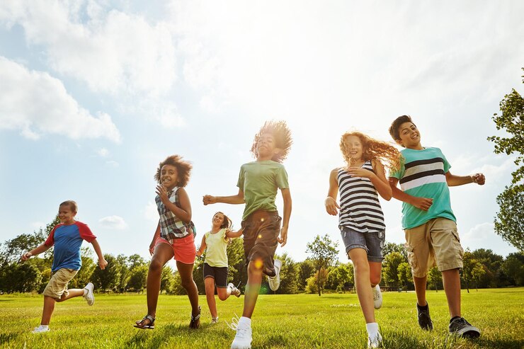Photo happy friends summer and running with kids in nature for fun playful day or sunshine at park diversity or group of excited children or youth enjoying sunny outdoor holiday on grass field together