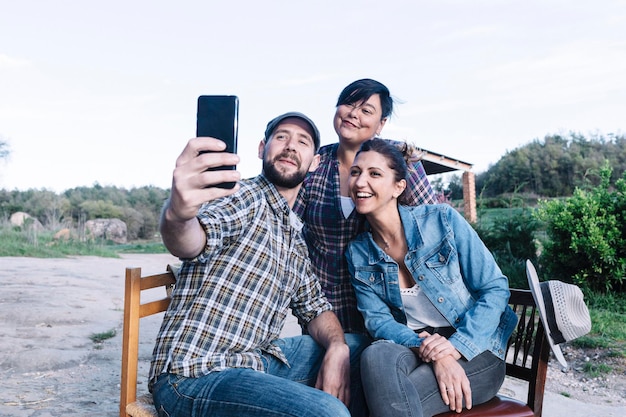 Happy friends taking selfie in rural area against clear sky