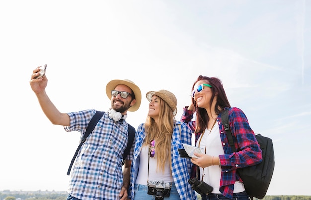 Photo happy friends taking selfie on smartphone at outdoors