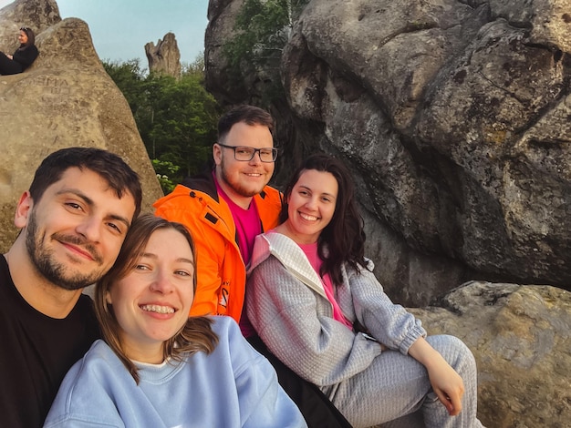 Photo happy friends taking selfie on sunset on the top of the cliff