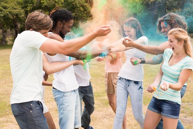 Photo happy friends throwing powder paint