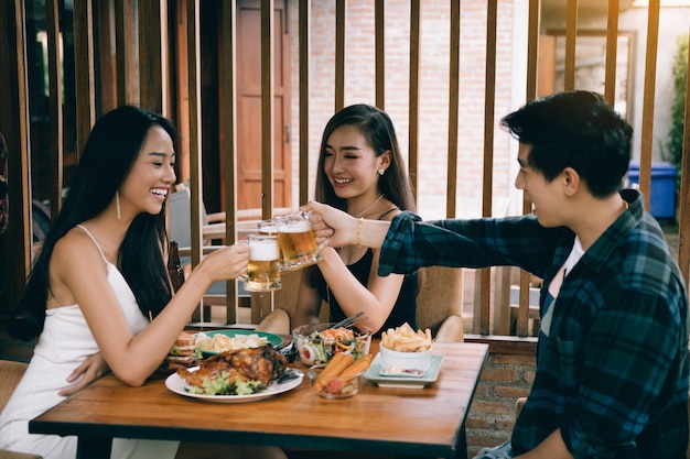 レストランでビールグラスを乾杯する幸せな友達