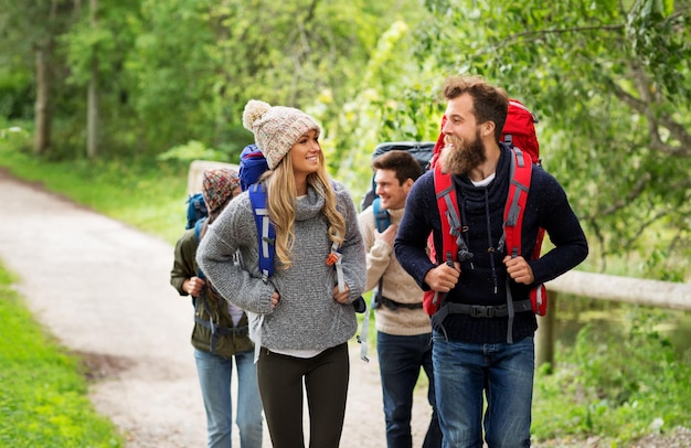 happy friends or travelers hiking with backpacks