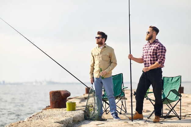 Photo happy friends with fishing rods and beer on pier