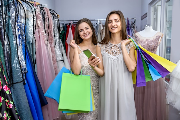 Happy friends with shopping bags in dress store