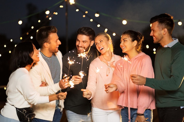 happy friends with sparklers at rooftop party