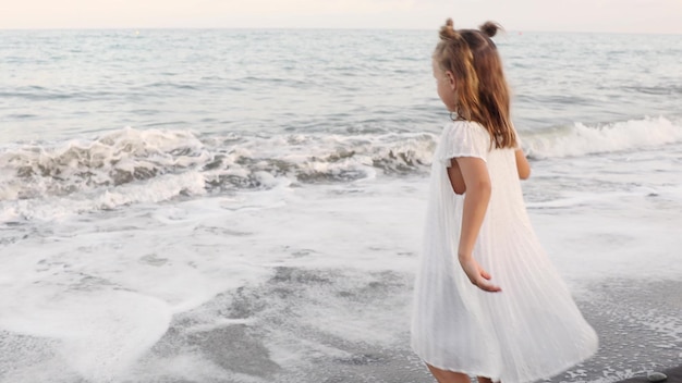 Photo happy fun smiling toddler girl spends time by the sea enjoy running near the sea on vacation