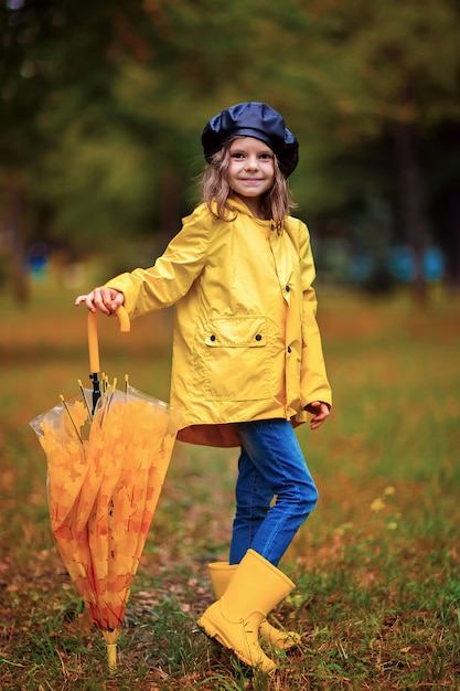 Happy funny child girl with umbrella in rubber boots