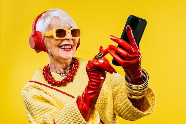 색색의 배경에 세련된 옷 초상화가 있는 행복하고 재미있는 멋진 노부인 생활 방식과 노인에 대한 사치스러운 스타일 개념을 가진 젊은 할머니