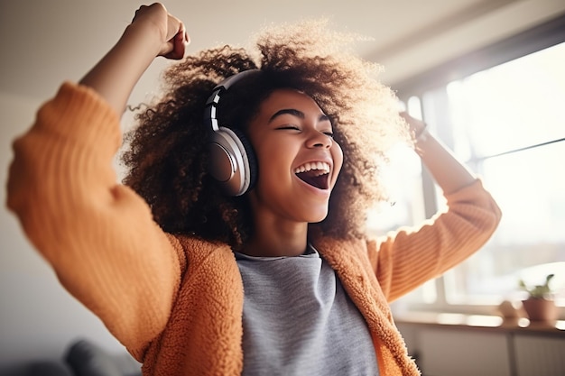 Happy funny gen z hipster African American teen girl wearing headphones dancing at home.