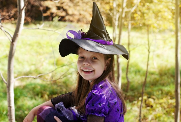 Happy funny schoolgirl in carnival costume on Halloween in the park