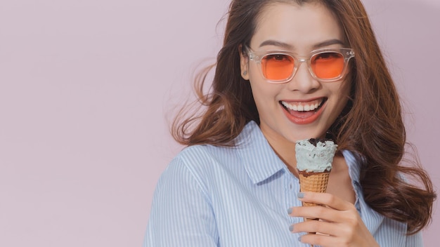 Happy funny young woman with long brown hair eating ice cream having fun.