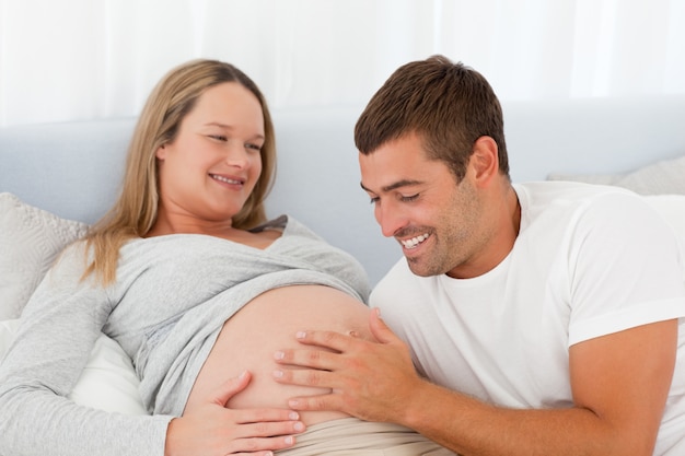 Papà futuro felice che tocca la pancia di sua moglie mentre rilassandosi